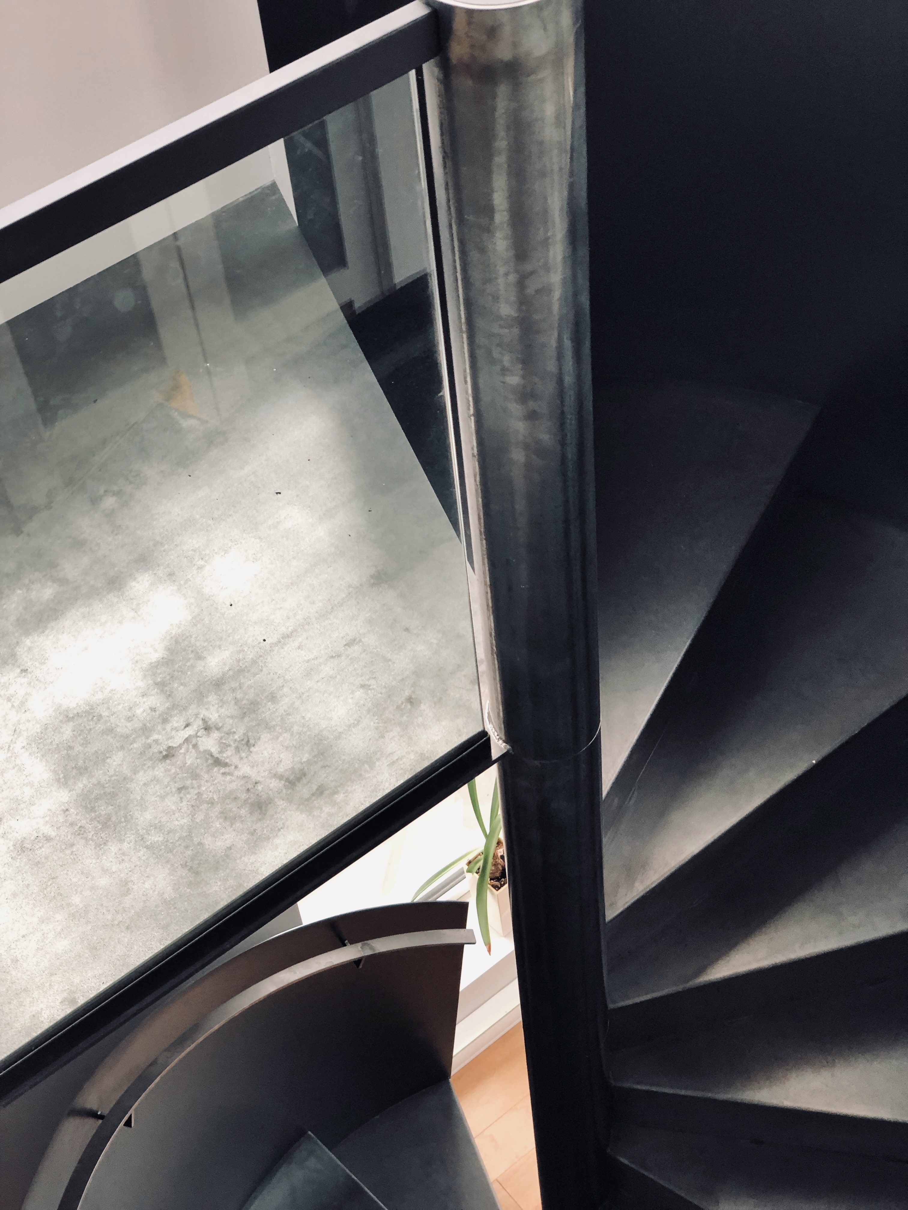 Vue d’ensemble d'un escalier fait d'acier et de verre en colimaçon, intégré avec soin à l’espace.